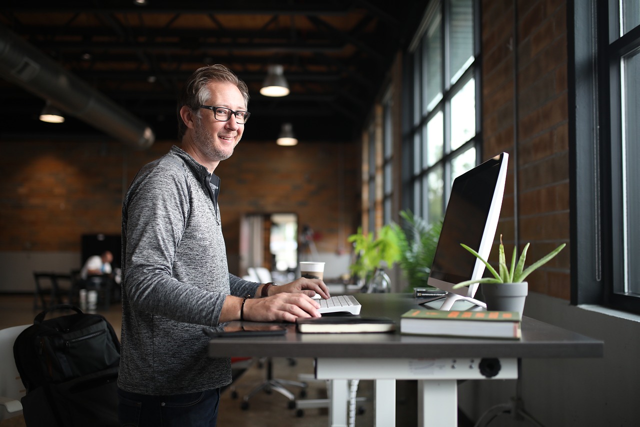 a man standing at a desk with a computer